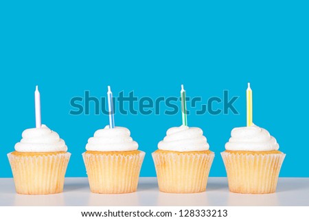 Vanilla cupcakes with candles with a blue background