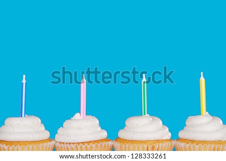 Vanilla cupcakes with candles with a blue background