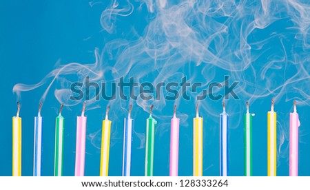 Birthday candles in a row blown out  with smoke on a blue background