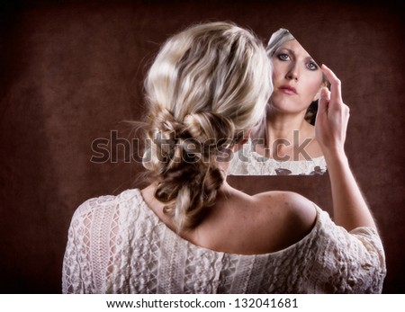 Woman looking into a broken mirror with a sad look,  back of head showing