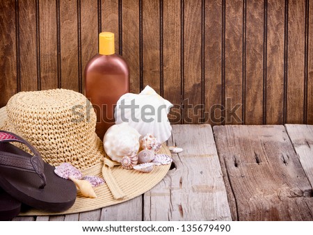 Sun hat, sandals and sun lotion with shells on wooden background