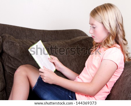 teen reading a book while relaxing or sitting on couch
