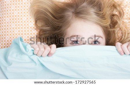 Child or teen hiding under covers in bed