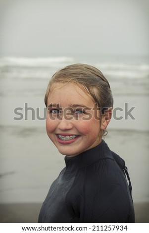 Girl wearing wet suit just out of water dripping wet on Rockaway beach Oregon