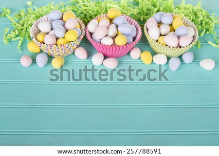 Easter Candy in colorful cupcake wrappers with green confetti on a turquoise blue wooden panel