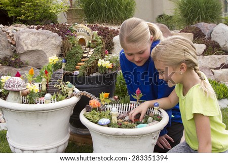 Two young girls helping to make fairy garden in a flower pot