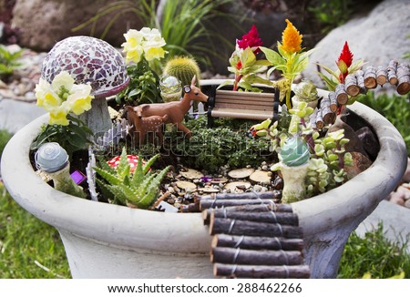 Fairy garden with deer, gazing balls and mushrooms in a flower pot