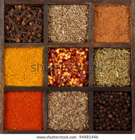 assorted herbs and spices in a decorative box, cloves, nutmeg, curry, chili powder, crushed chillies, dill seed, thyme, peppercorn, anise