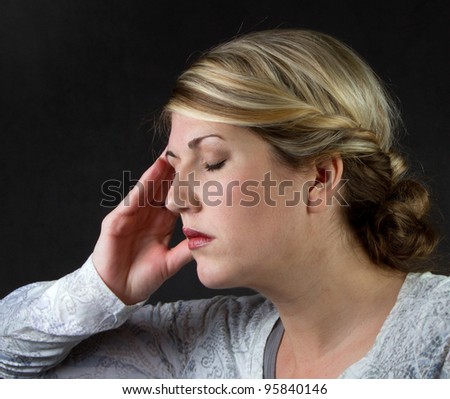 A woman with a headache against a dark background