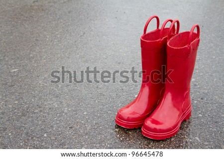 Red rain boots on wet pavement, room for copy space