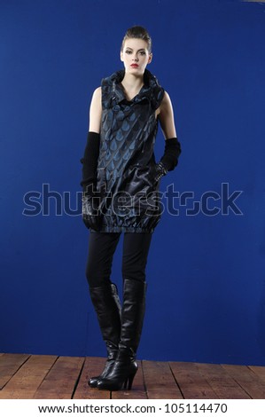 Full length fashion model in elegant dress posing wooden floor on blue background