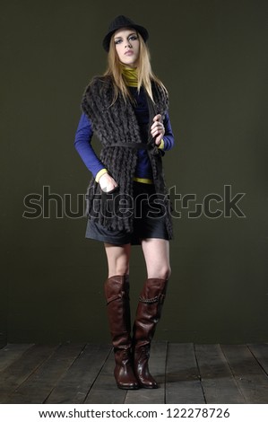 Full length fashion girl in boots standing posing on wooden floor