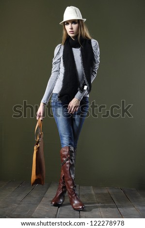 Full length fashion girl in hat with bag walking on wooden floor