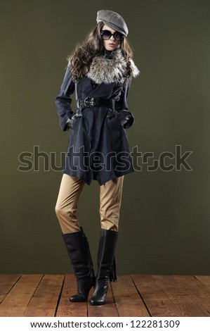 Full length Beautiful fashion girl in sunglasses with coat standing posing on wooden floor