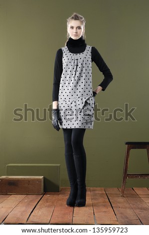 Full length Beautiful fashion girl in cube standing with chair posing on wooden floor