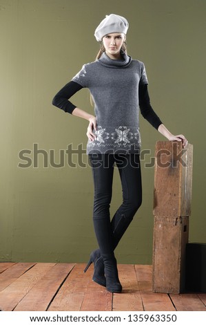 Full length young woman posing with cube on wooden floor
