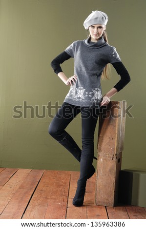 Full length portrait of pretty young woman near cube posing wooden floor