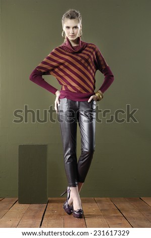 Full length young woman posing with cube on wooden floor