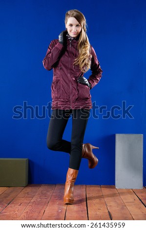 Beautiful fashion girl in gloves standing posing on wooden floor