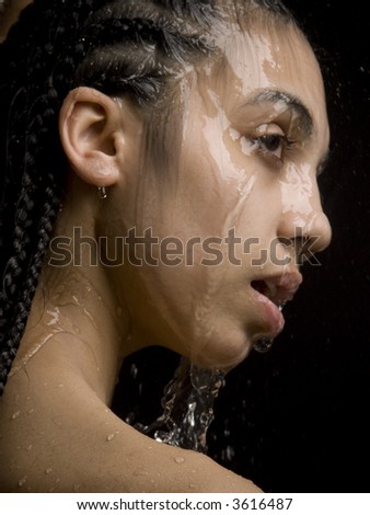 The black girl under jets of water in studio