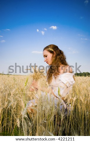 The woman in light clothes costing on a wheaten floor on a background of the dark blue sky