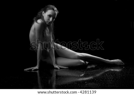 Black-and-white photo of the naked girl of the dancer on a black background with reflection