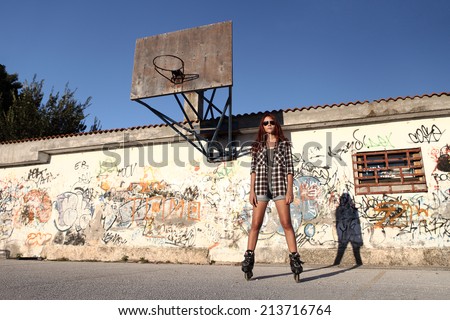 girl with roller skates on graffiti background and a basketball hoop
