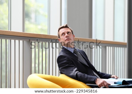 business man sitting with documents folder open looks up the window
