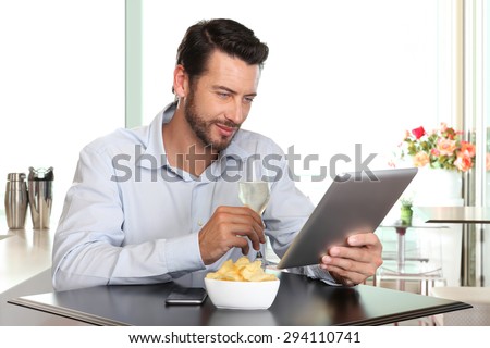 happy man with wine  and tablet at the bar