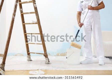painter man at work with a paint roller and ladder, hand close up