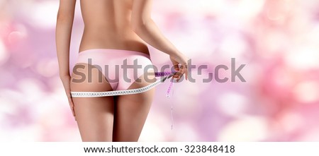 hand with meter, bum and legs of slim woman over pink background