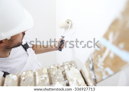 painter man at work with a paint roller, on ladder, wall painting concept