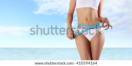 woman holding blue meter with hands near waistline, isolated on summer sky and sea  background