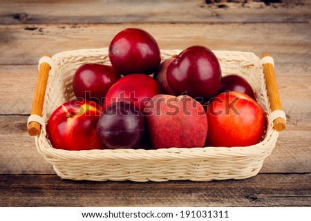 Plums, Nectarines and Peaches in a Woven Basket on Age Wooden Table