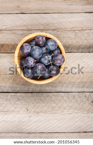 Ripe Plums in a Bamboo Bowl on Rustic Wooden Table