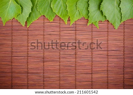 Fresh Natural Green Leaves on Dark Brown Bamboo Mat, Ecology Background