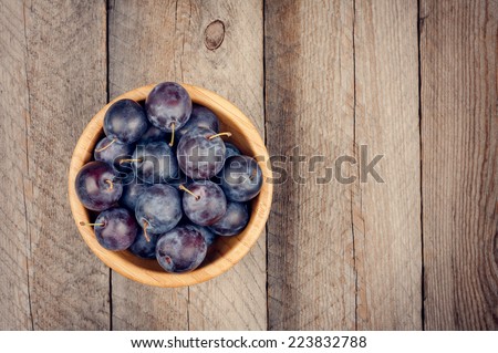 Fresh Plums in Wooden Bowl on Wooden Tabletop