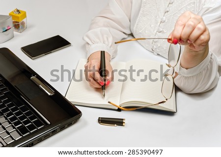 Close-up of female hands with laptop computer, smartphone and office tools on table