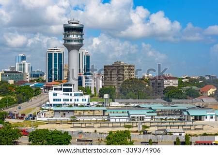 Modern glass skyscrapers stand alongside older buildings in Dar Es Salaam with maritime control tower on foreground