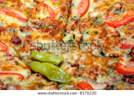 Close-up view to chicken pizza with pepperoni, tomato, mozzarella and spinach. Shalow depth of field.