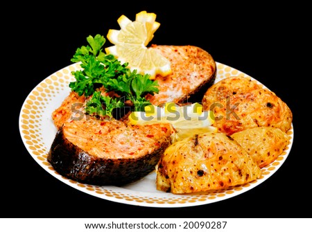 Baked fish with potato, lemon and species on plate on black background. Shallow depth of field. Not isolated, shot in studio on black.