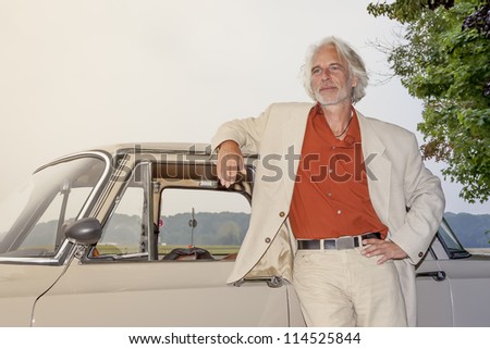An image of a man in front of his car