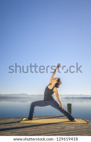 An image of a pretty woman doing yoga at the lake - Parivrtta Parshvakonasana