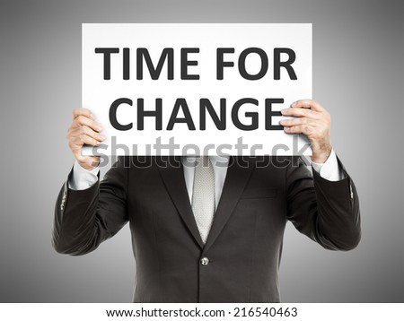 A business man holding a paper in front of his face with the text time for change