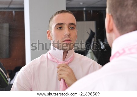Businessman ties his neck-tie in front of mirror