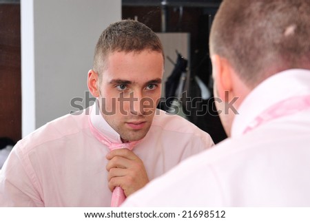 Businessman ties his neck-tie in front of mirror
