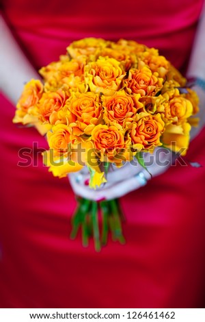 woman in a red dress holding a bouquet of orange roses