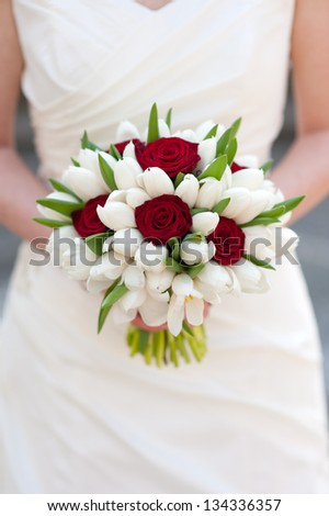 bride holding red rose and white tulip wedding bouquet