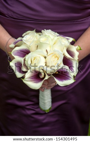 bride holding a wedding bouquet of purple plus white roses and calla lilies