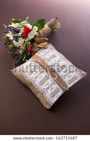 Vintage wedding pillow with ring and field flowers bouquet on pink background